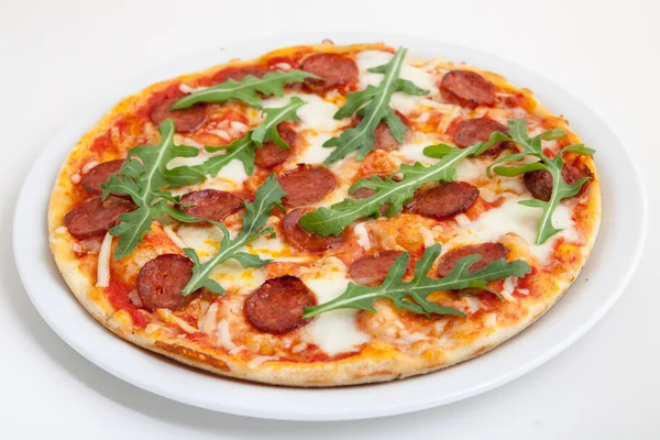 Pizza con salame, formaggio e rucola su piatto bianco — Foto Stock