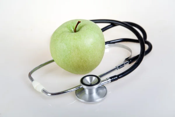 Medizinisches Stethoskop und grüner Apfel. Gesundes Essen — Stockfoto