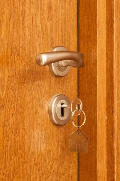 Handle pintu dengan kunci disisipkan dalam lubang kunci dan ikon rumah di atasnya — Stok Foto