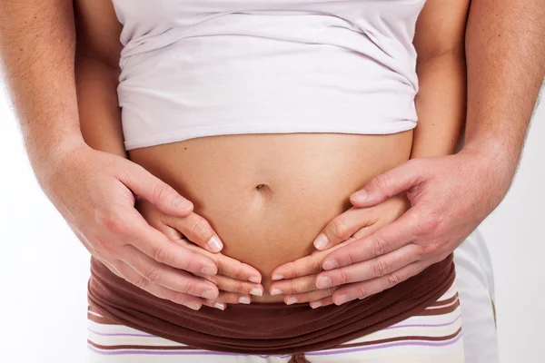 Mani di mamma e papà che tengono una pancia di donna incinta — Foto Stock