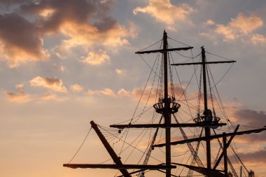 Masts of a pirate ship on sunset clipart