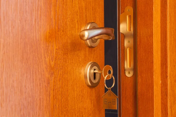 Offene Tür mit eingestecktem Schlüssel im Schlüsselloch und Haussymbol darauf — Stockfoto