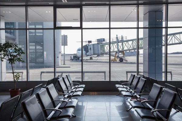 Bench in airport terminal and parked airplane — Stock Photo, Image