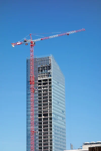 Hoisting tower crane on top of construction skyscraper building over blue sky — Stock Photo, Image