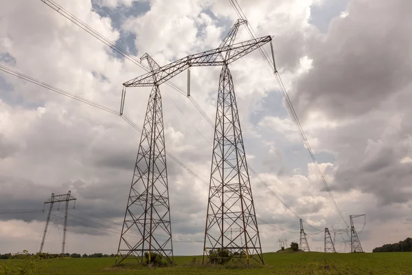 Electricity pylons and cable lines against cloudy sky — Stock Photo, Image