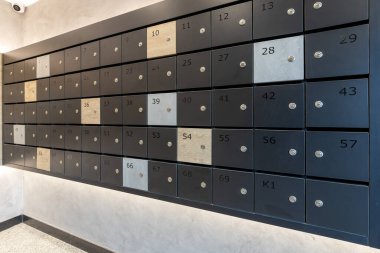 Çağdaş bir apartman lobisinde numaraları ve kilitleri olan modern posta kutuları. Mektup ve posta iletimi için güvenli posta kutusu paneli..