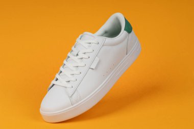 Sarı arka planda beyaz spor ayakkabı. Günlük moda, spor giyim ve sokak kıyafetleri için modern ve şık ayakkabılar..