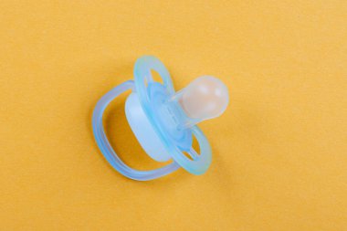 Sarı Arkaplanda Mavi Bebek Emziği. Çocuk Bakımı ve Ebeveynlik Konsepti ile Yeni Doğanlar İçin Rahatlık, Doğum Bildirisi ve Çocuk Bakımı Özellikleri