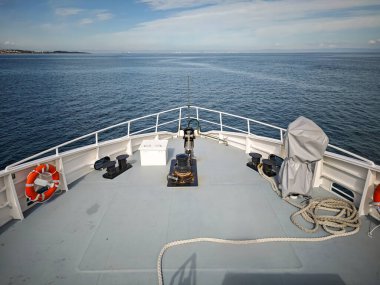 Açık denizde seyreden bir feribotun pruvasından. Deniz yolculuğu, ulaşım ve tatil macerası konsepti. Güneşli bir günde ufka doğru yol alan bir yolcu gemisi..