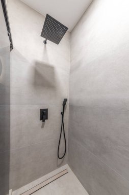 Şık, modern duşlar, siyah mat eşyalar, sağanak yağmur başlığı ve gri fayanslar. Çağdaş bir ev ya da otel için şık bir banyo tasarımı..