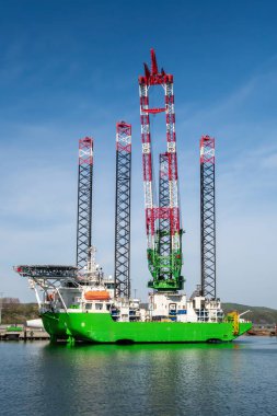 Limana yanaşmış Uzun Bacaklı Offshore İnşaat Gemisi. Endüstriyel Denizcilik Gemisi Rüzgâr Çiftliği Kurulumu ve Ağır Açık Deniz Mühendisliği