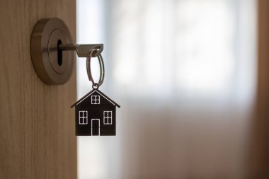 Yeni bir eve açılan kapı. Anahtarlı kapı kolu ve ev şeklindeki anahtarlık. İpotek, yatırım, gayrimenkul, mülk ve yeni konut kavramı