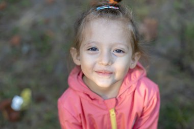 Dışarıda gülümseyen sevimli küçük bir kız.