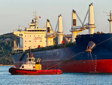 Römorkör büyük kargo gemisine yardım ediyor. Römorkör eşliğinde büyük kargo gemisi limana giriyor..