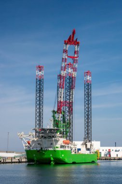 Limana yanaşmış Uzun Bacaklı Offshore İnşaat Gemisi. Endüstriyel Denizcilik Gemisi Rüzgâr Çiftliği Kurulumu ve Ağır Açık Deniz Mühendisliği
