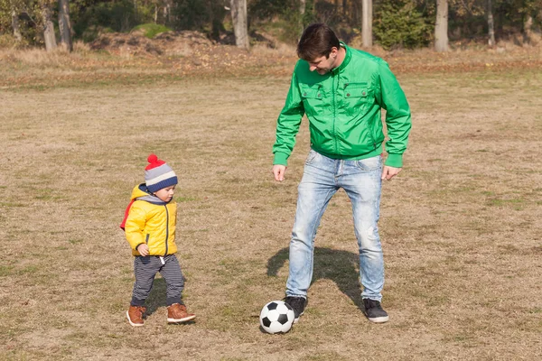 Padre joven con su pequeño hijo jugando fútbol, fútbol en el parque —  Fotos de Stock
