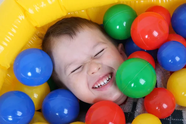 Little smiling boy playing in colorful balls playground — Stock Photo, Image