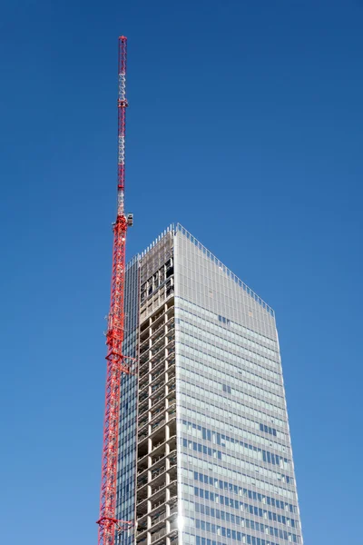 Hoisting tower crane on top of construction skyscraper building over blue sky — Stock Photo, Image