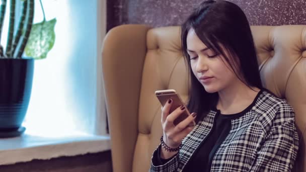 Beautiful girl with the phone. Woman using app on smartphone in cafe. Texting on mobile phone. — Stock Video