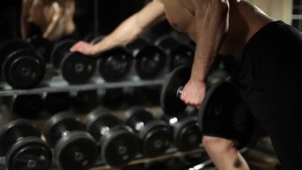 Un tipo en el gimnasio. Hace ejercicios con pesas . — Vídeos de Stock