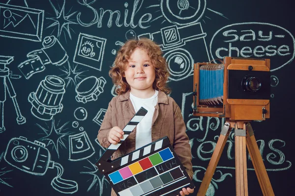 Mały chłopiec stojący w pobliżu aparat na czarnym tle z napisem — Zdjęcie stockowe