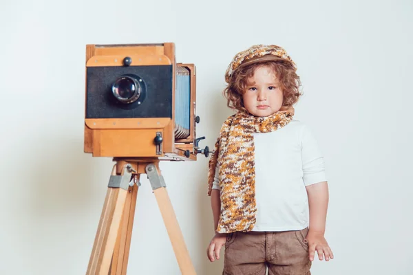 Mały chłopiec stojący w pobliżu aparat na białym tle — Zdjęcie stockowe