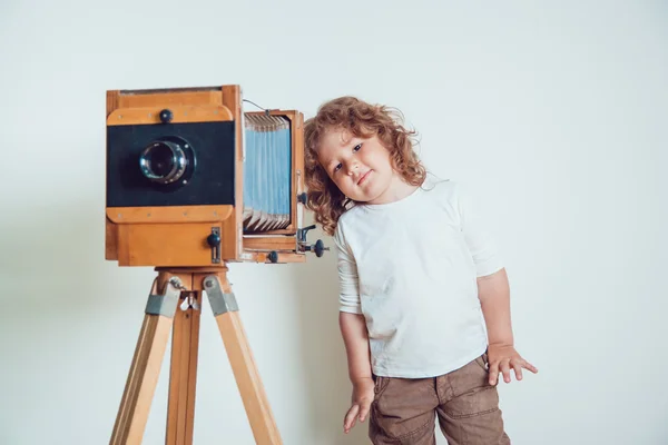 Маленький мальчик стоит рядом с камерой на белом фоне — стоковое фото