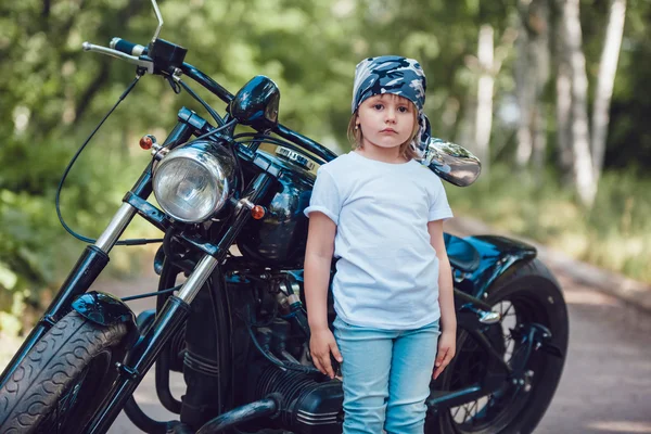 Dziewczynka w biały T-shirt i chustka stojący w pobliżu motocykl — Zdjęcie stockowe