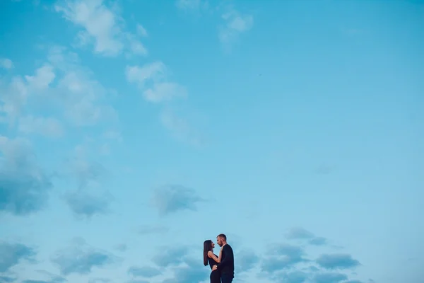 Kärlekshistoria. Par i solnedgången. På bakgrund av himlen. Moln. — Stockfoto