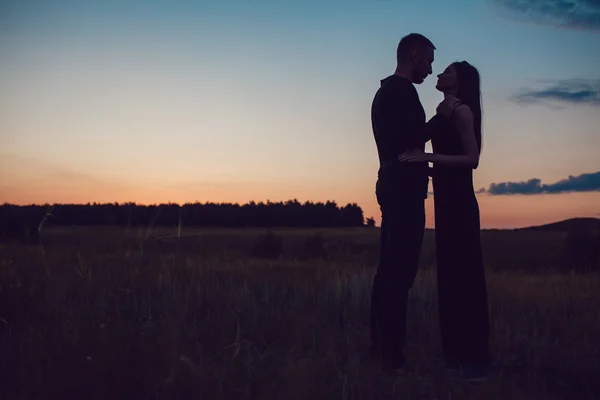 Het verhaal van de liefde. Paar bij zonsondergang. Op de achtergrond van de hemel. Wolken. — Stockfoto