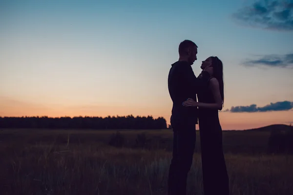 Het verhaal van de liefde. Paar bij zonsondergang. Op de achtergrond van de hemel. Wolken. — Stockfoto