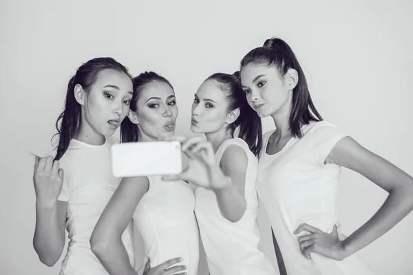Amigos positivos retrato de cuatro chicas felices haciendo selfie, caras divertidas seguro, muecas, alegría, emociones, estilo casual, colores pastel, pared blanca. Una mujer loca y divertida. Fondo blanco . — Foto de Stock