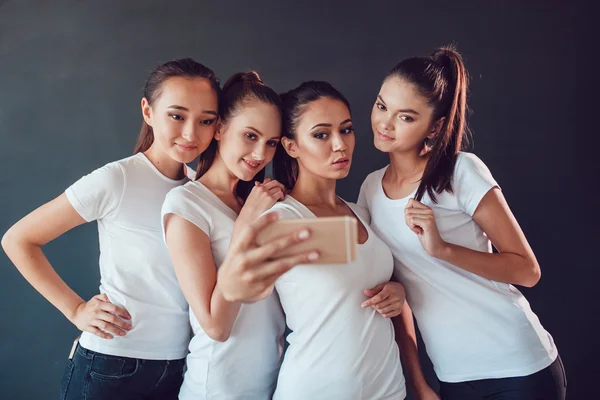 Positive friends portrait of happy girls making selfie, sure funny faces, grimaces, joy, emotions, casual style, pastel colors. Dark background. — Stock Photo, Image