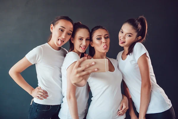 Positive friends portrait of happy girls making selfie, sure funny faces, grimaces, joy, emotions, casual style, pastel colors. Dark background. — Stock Photo, Image