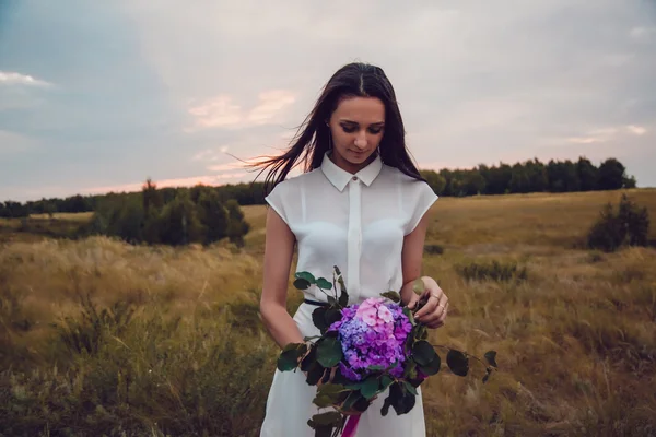 Ao ar livre retrato de uma linda jovem morena segurando flores de lavanda . — Fotografia de Stock