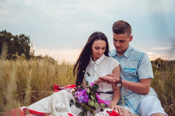 Krásná mladá šťastné milující pár na piknik vleže na pléd na slunečný letní den těší a odpočívá. objímání a při pohledu na sebe a s úsměvem. — Stock fotografie