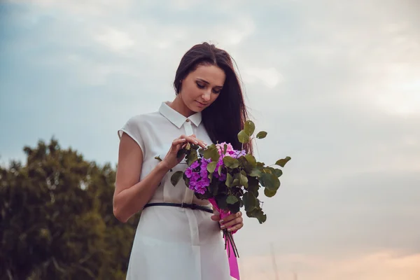 Ao ar livre retrato de uma linda jovem morena segurando flores de lavanda . — Fotografia de Stock