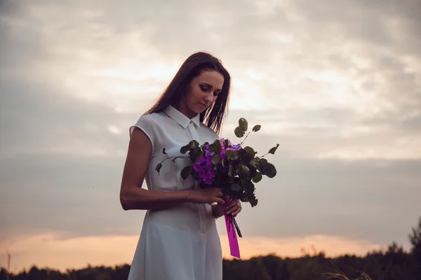 Ao ar livre retrato de uma linda jovem morena segurando flores de lavanda . — Fotografia de Stock