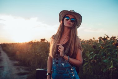Ayçiçeği bir alanda kovboy şapkalı kız. Günbatımı