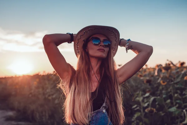 Uma rapariga de chapéu de cowboy num campo de girassol. Pôr do sol — Fotografia de Stock