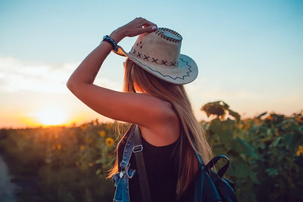 Meisje in een cowboyhoed in een zonnebloem veld. Zonsondergang — Stockfoto
