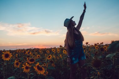 Kovboy şapkalı kız ayçiçeği alan yakalar bir cep telefonu kaybetti. Günbatımı.