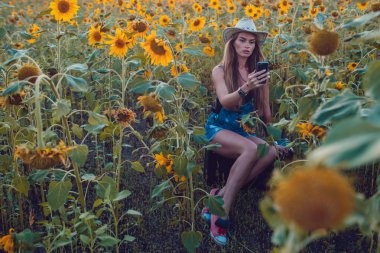 Kovboy şapkalı kız ayçiçeği alan yakalar bir cep telefonu kaybetti. Günbatımı.