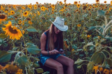 Kovboy şapkalı kız ayçiçeği alan yakalar bir cep telefonu kaybetti. Günbatımı.