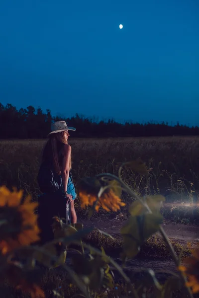 Ella perdió en el campo de girasol se sienta en una maleta. Esperando ayuda. Noche. . —  Fotos de Stock