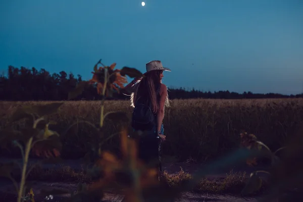 Ella perdió en el campo de girasol se sienta en una maleta. Esperando ayuda. Noche. . —  Fotos de Stock