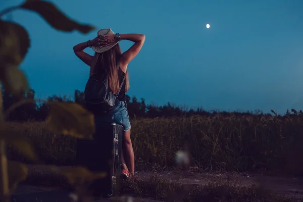 Ztratila v slunečnicová pole sedí na kufru. Čeká na pomoc. Noční. — Stock fotografie