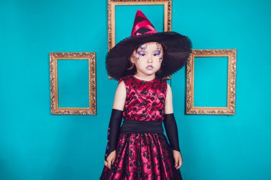 Cadı kostüm turkuaz duvar bir arka plan üzerinde küçük kız