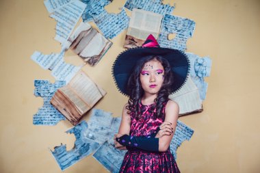 Kız sarı duvar arka plan üzerinde duran cadı kostüm