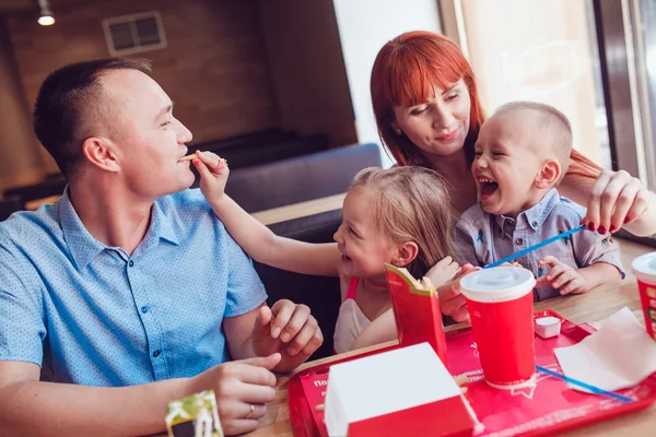 Familia feliz comiendo comida rápida en el restaurante todos juntos — Foto de Stock